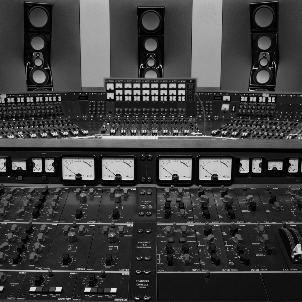 Ein Blick auf ein professionelles Tonstudio mit Mischpult und Lautsprechern im Hintergrund.